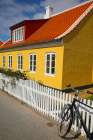Skagen, Denmark. Bike, yellow house with white picket fence and terra cotta roof. Art Print